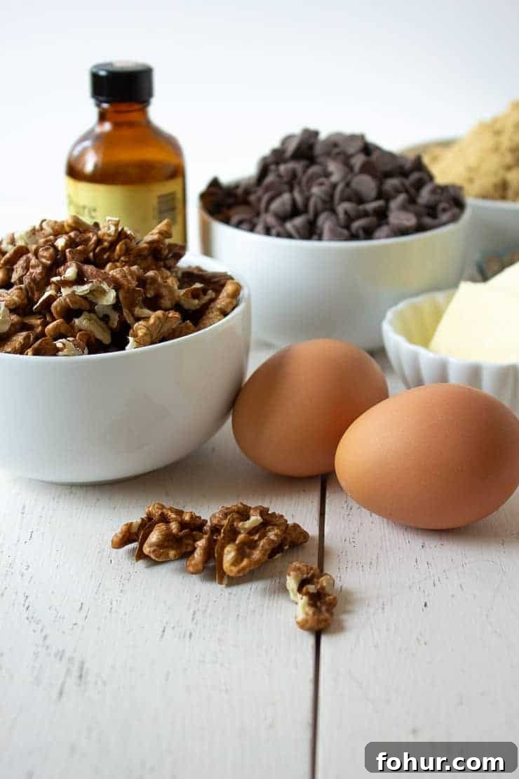 Decadent Chocolate Walnut Tart Recipe 2 White bowls filled with walnuts, chocolate chips and butter along with eggs and vanilla.