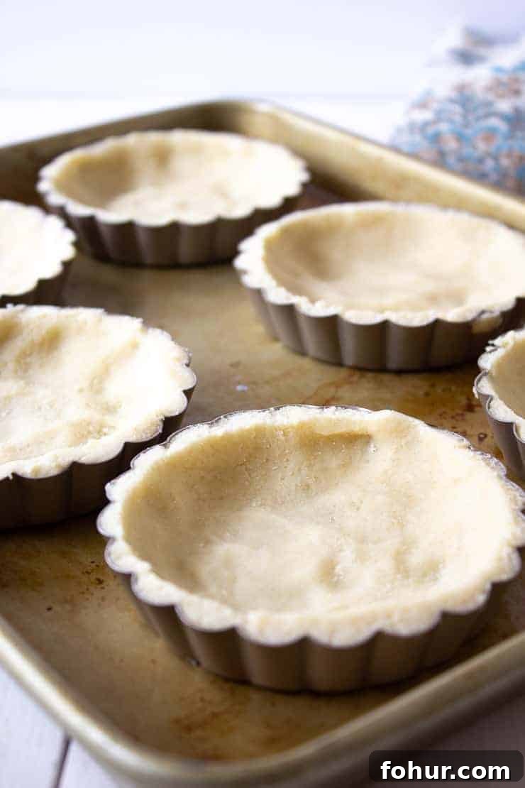 Decadent Chocolate Walnut Tart Recipe 3 Pastry crusts in mini tart pans on a baking sheet.