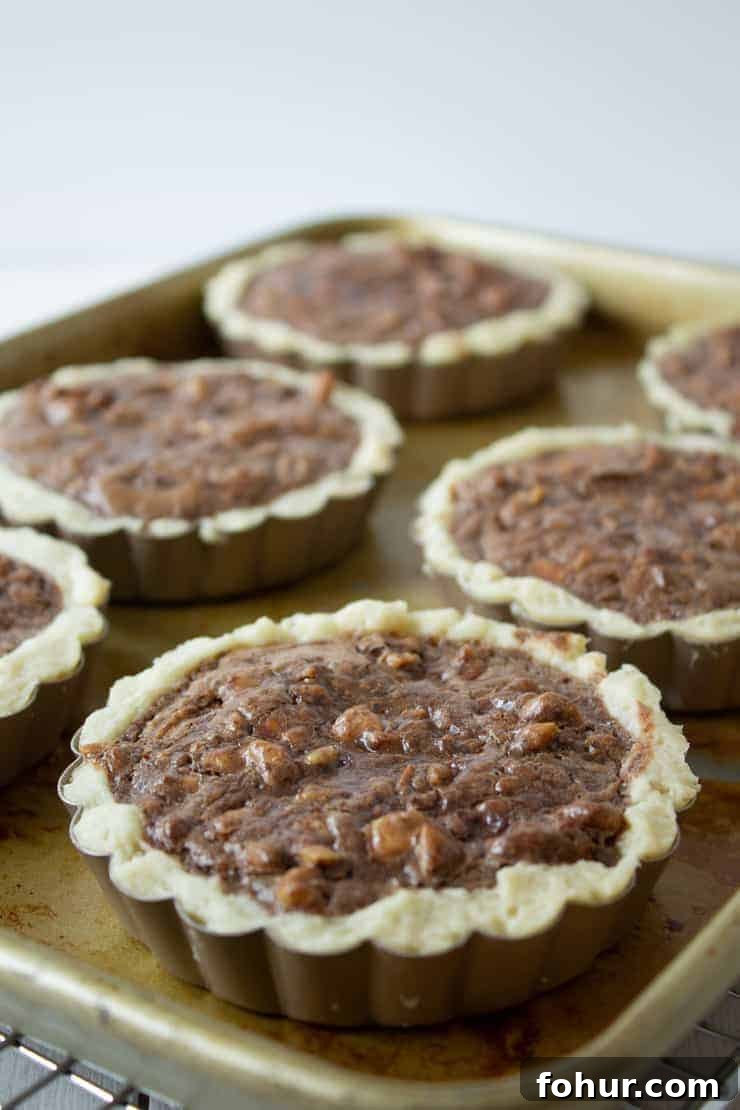 Decadent Chocolate Walnut Tart Recipe 6 Chocolate Walnut Tarts cooling on a baking sheet.