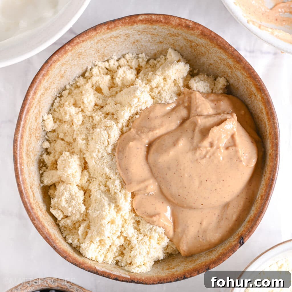 No-Bake Edible Protein Cookie Dough Recipe 10 A scoop of creamy peanut butter added to the protein powder in the mixing bowl.