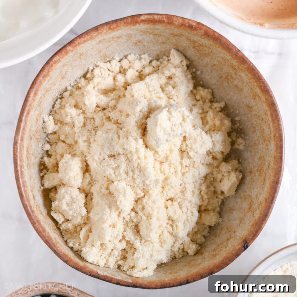 No-Bake Edible Protein Cookie Dough Recipe 4 A ceramic bowl filled with vanilla protein powder, the base ingredient for protein cookie dough.