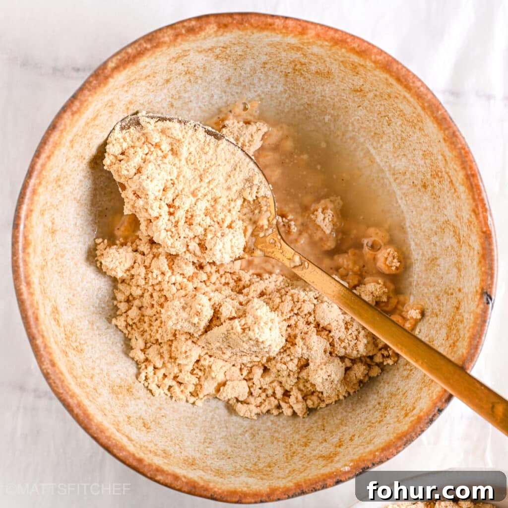 No-Bake Edible Protein Cookie Dough Recipe 9 Powdered peanut butter and water in a ceramic bowl ready to be mixed with water.