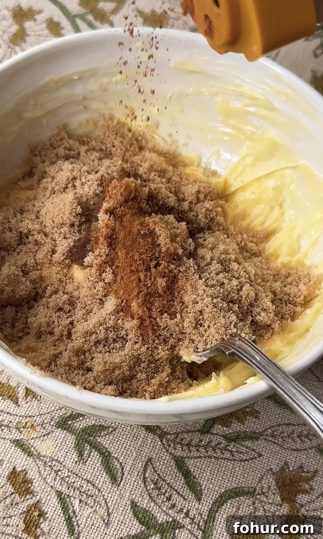 Mashing butter and sugar in bowl with spoon.
