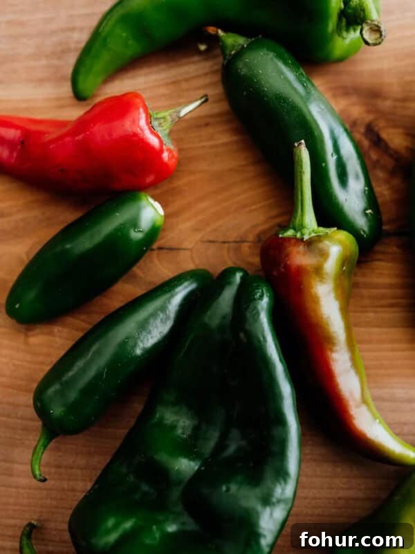 assorted fresh Mexican chiles on a wooden board