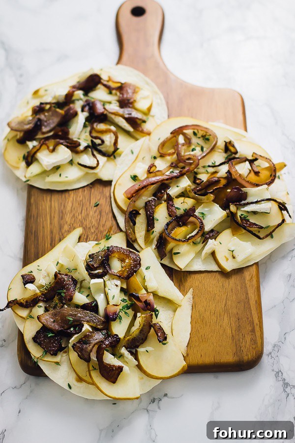 Vegan Pear and Brie Quesadilla Recipe with Caramelized Onions 2 Three tortillas with pear and brie slices on them.