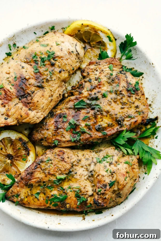 Cooked marinated chicken on a plate with green garnish.