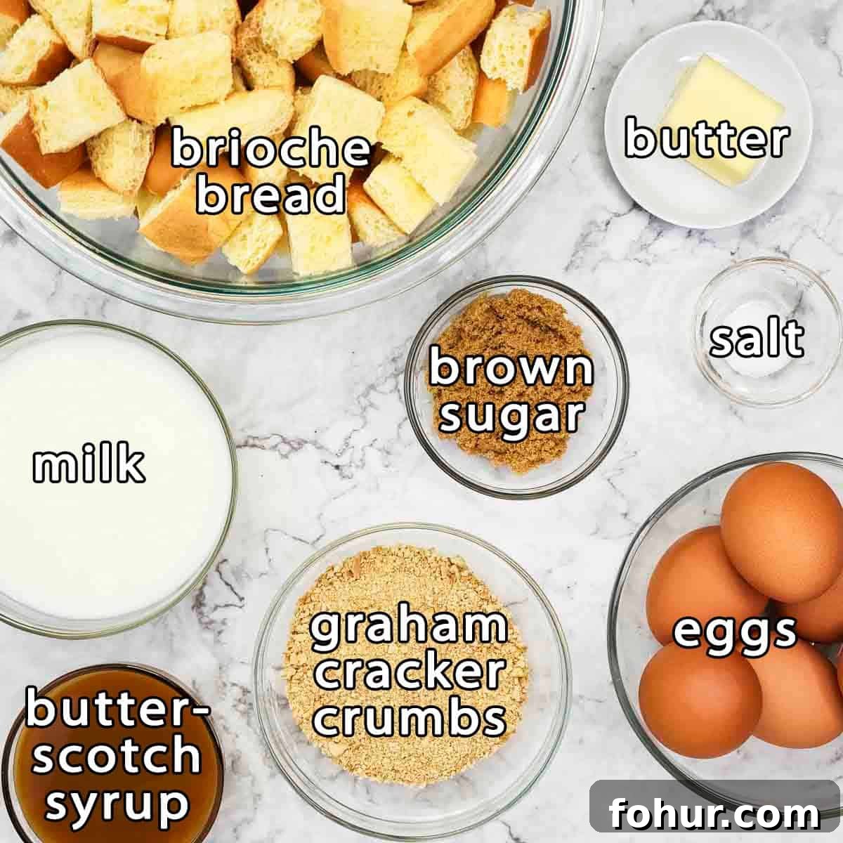 Brioche Baked French Toast with Butterscotch Sauce 3 Overhead shot of ingredients - brioche bread, butter, brown sugar, milk, butterscotch syrup, graham cracker crumbs, eggs, and salt.