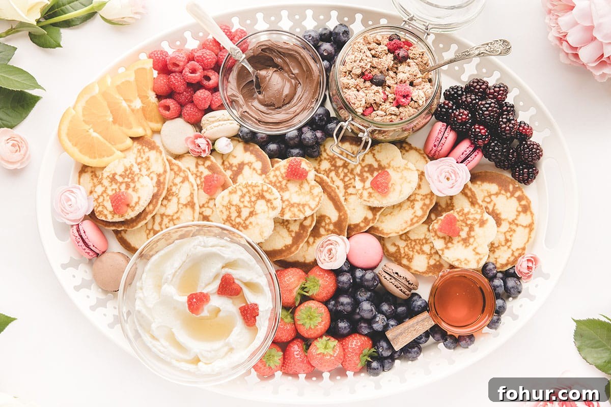 Valentine's Day Charcuterie Board for Two 9 Mini pancakes, berries, syrup, and granola on a white plate.