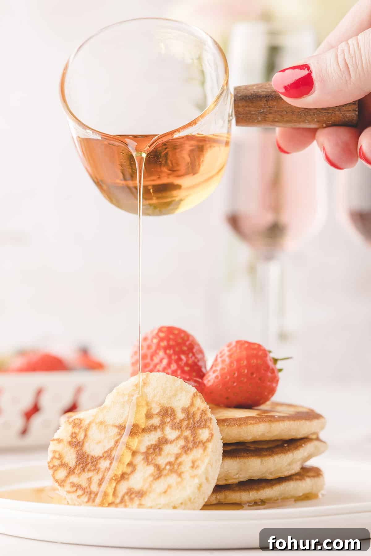 Valentine's Day Charcuterie Board for Two 4 hand holding jar of syrup pouring over pancakes.