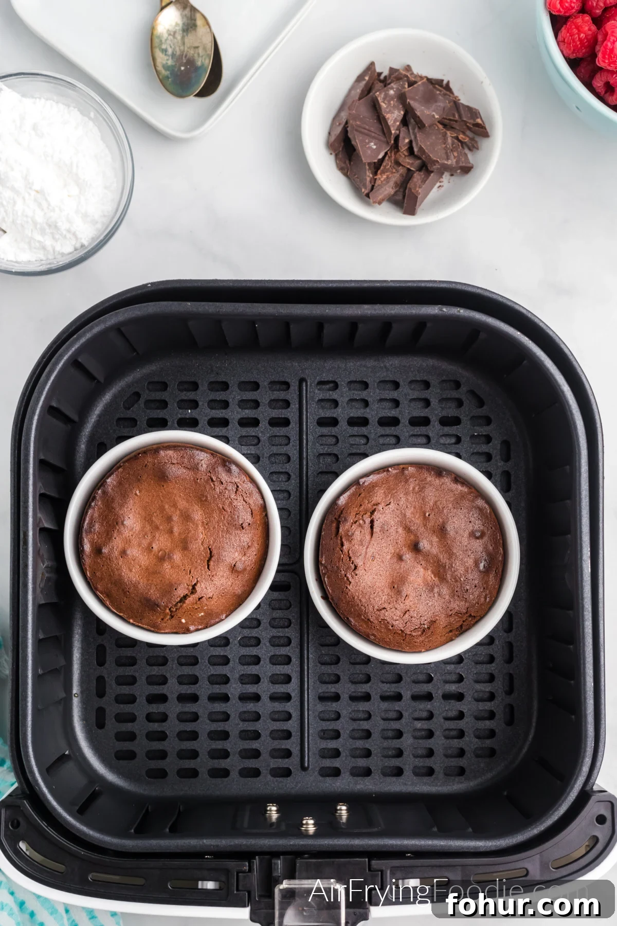 Lava cakes in ramekins in the basket of the air fryer.
