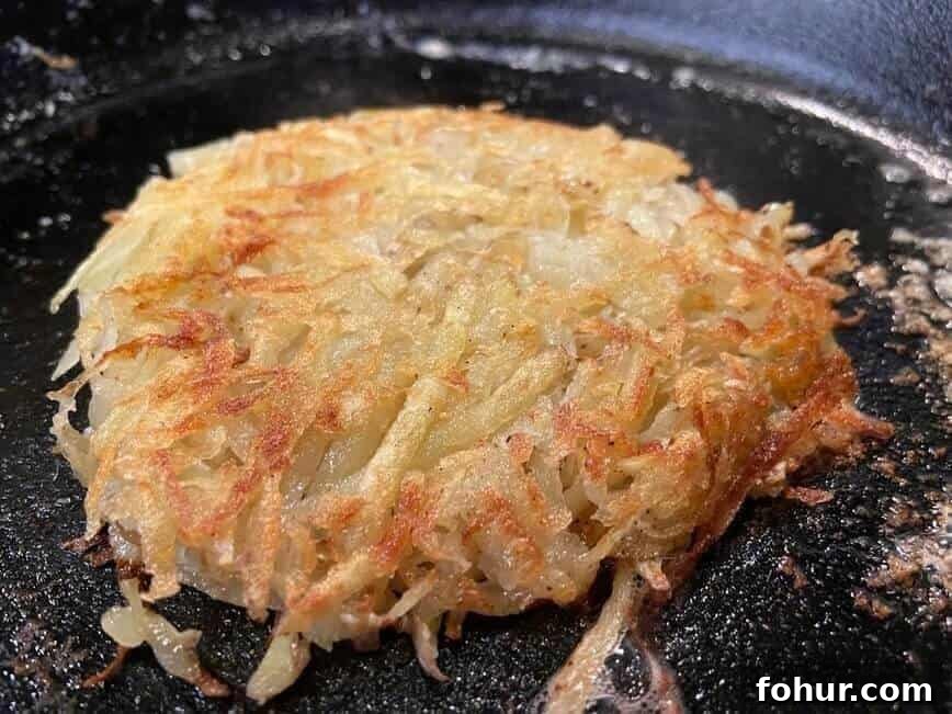 Crispy Buttery Hash Browns: How to Make Them 9 Hash brown patty browning in pan.
