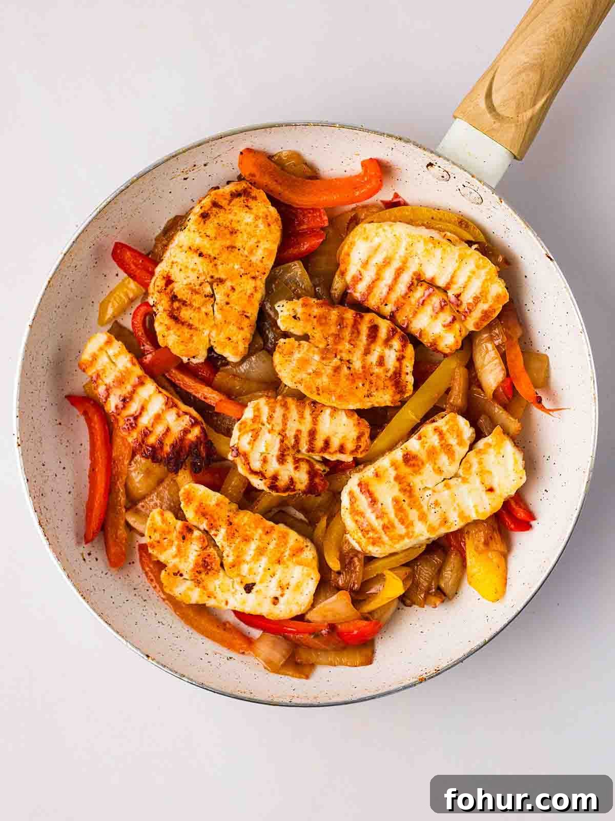 15-Minute Halloumi Fajitas with Peppers and Onions 7 A pan filled with cooked peppers, onion and slices of halloumi.