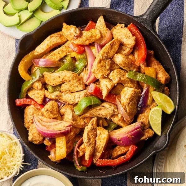 15-Minute Halloumi Fajitas with Peppers and Onions 9 A pan filled with cooked chicken fajitas on a table, with side dishes around, ready to eat.
