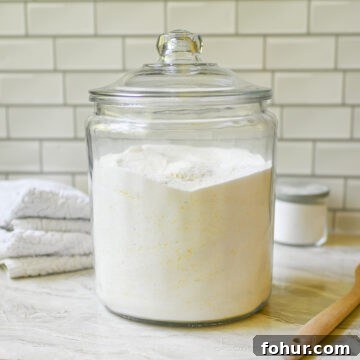 large glass jar of diy laundry deteregnt on a counter, surrounded by laundry supplies.
