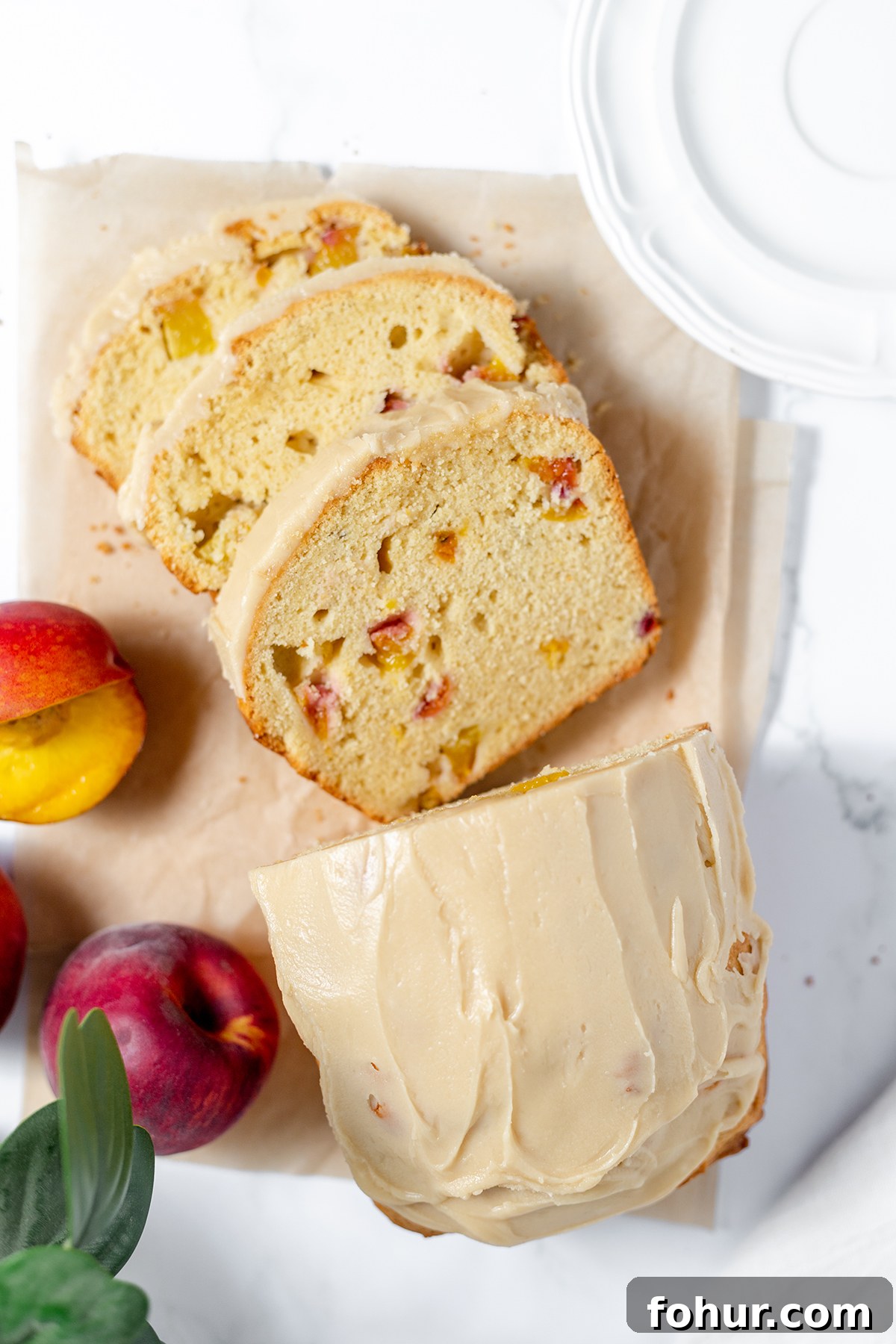 Moist Homemade Peach Bread Recipe with Cinnamon Glaze 2 Glazed peach bread with 3 slices laying on parchment paper.