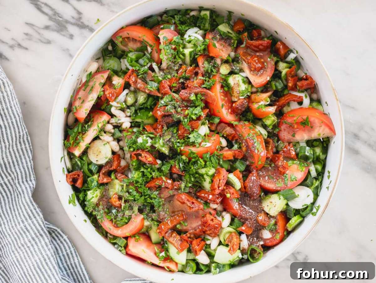 Hearty Mediterranean White Bean Salad with Herbs and Lemon 6 Step 3 Chopped tomatoes cucumber and herbs in a large bowl for white bean salad.