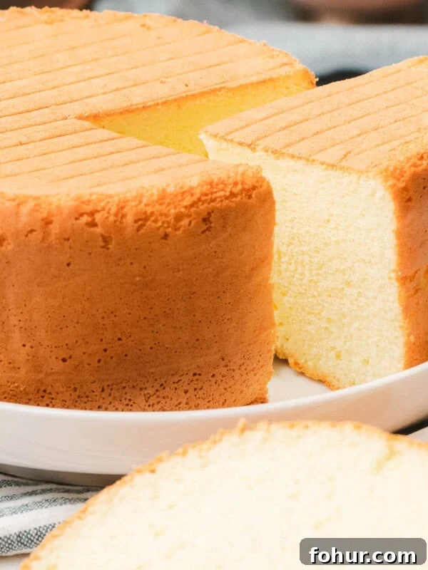 Easy sponge cake with slice taken out to reveal soft, fluffy, texture.