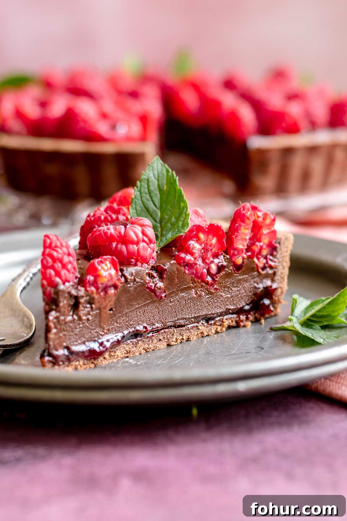 From Scratch Chocolate Raspberry Tart Recipe 2 A slice of chocolate rapsberry tart on plater.