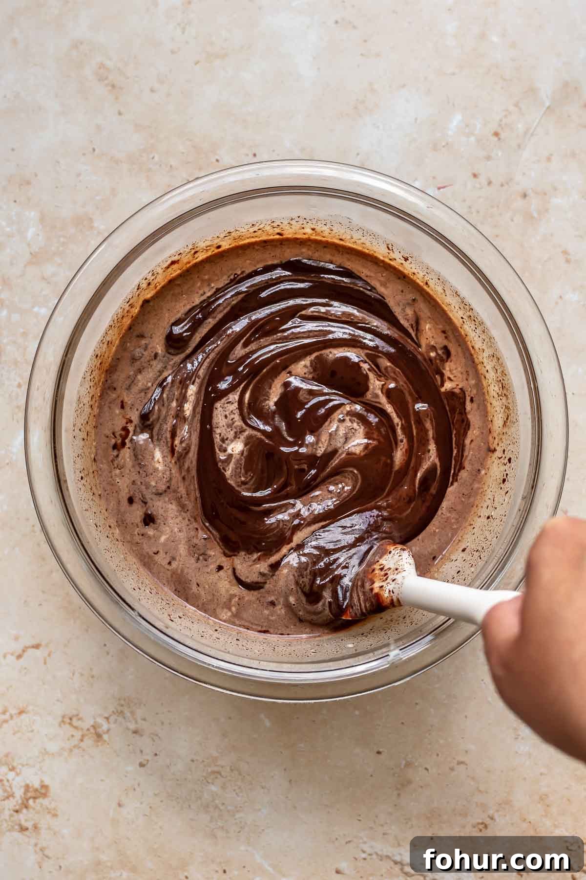 From Scratch Chocolate Raspberry Tart Recipe 7 A rubber spatula mixes together dark chocolate ganache in a bowl.