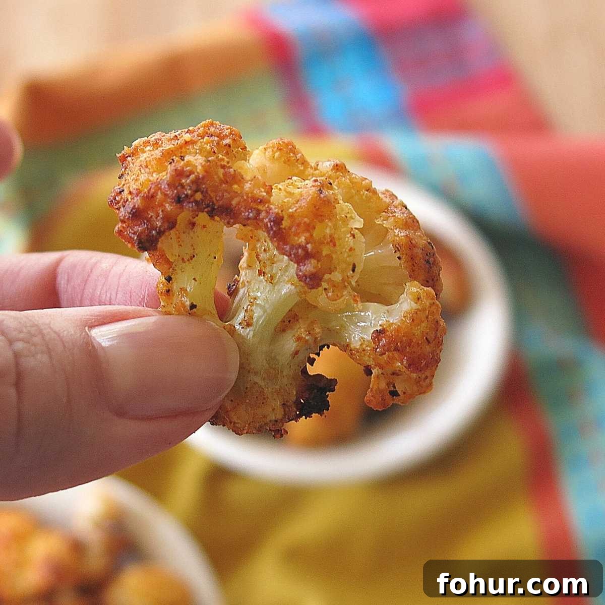 Crispy 5-Ingredient Parmesan Cauliflower Bites Recipe 3 Parmesan Cauliflower Appetizer being held by two fingers.