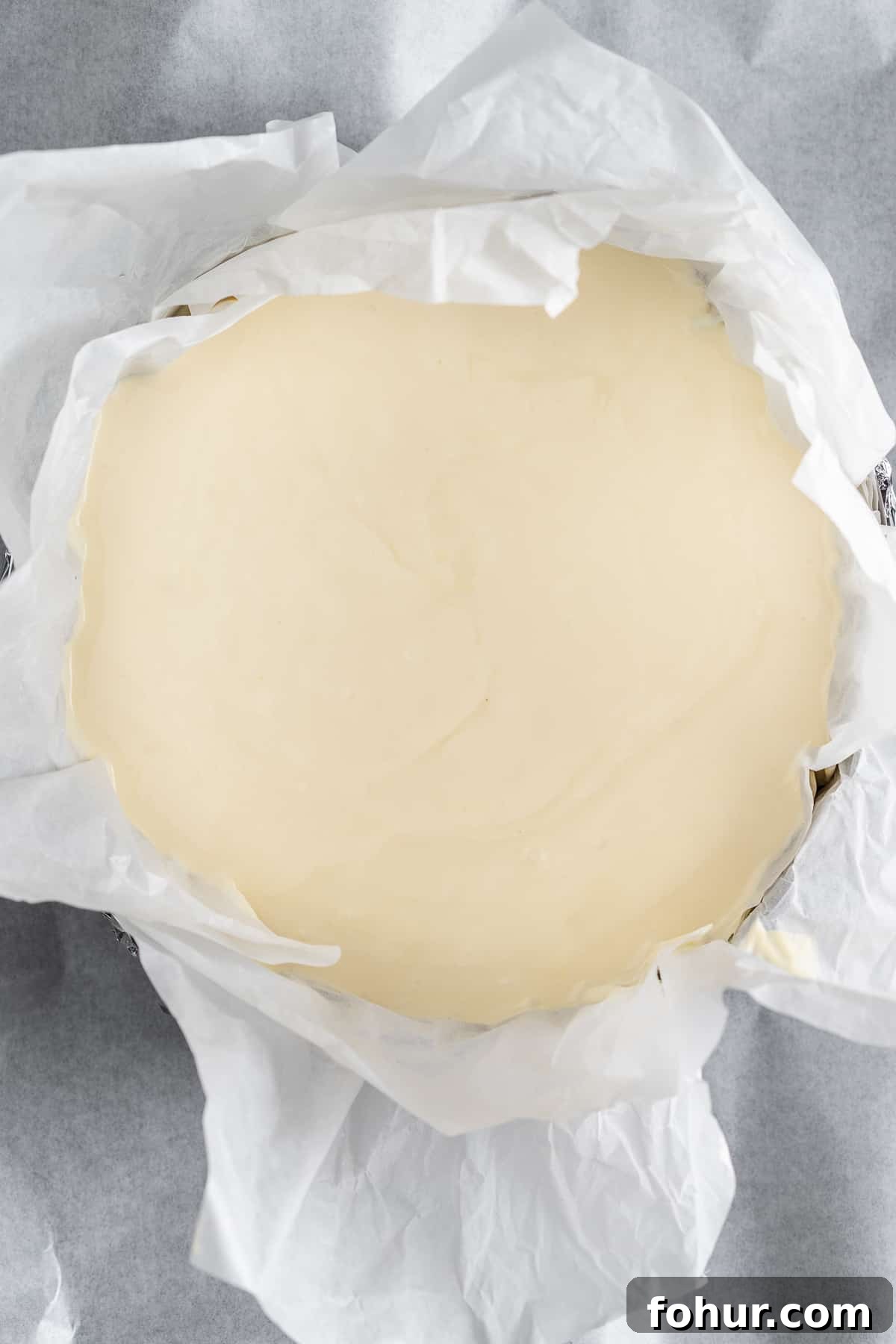 Cheesecake batter in a baking mold lined with parchment paper.