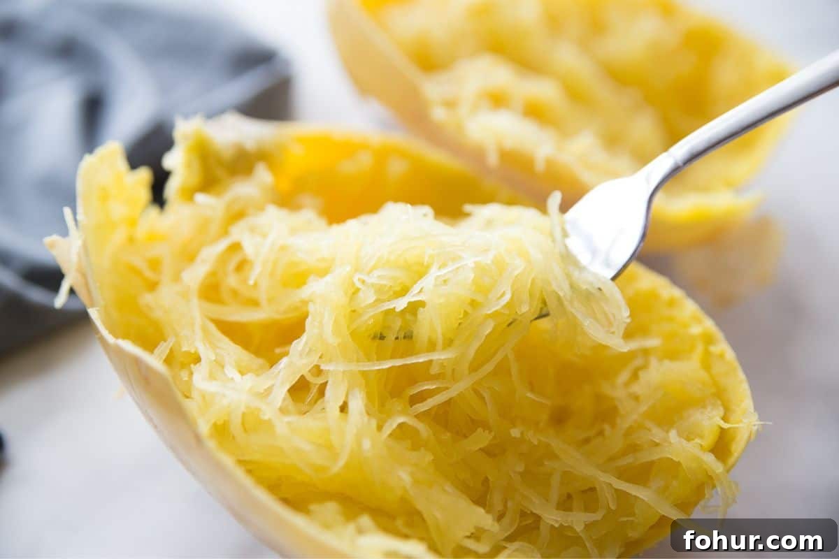 Low-Carb Spaghetti Squash Lasagna Recipe 3 A fork full of cooked spaghetti squash noodles inside of a squash boat.