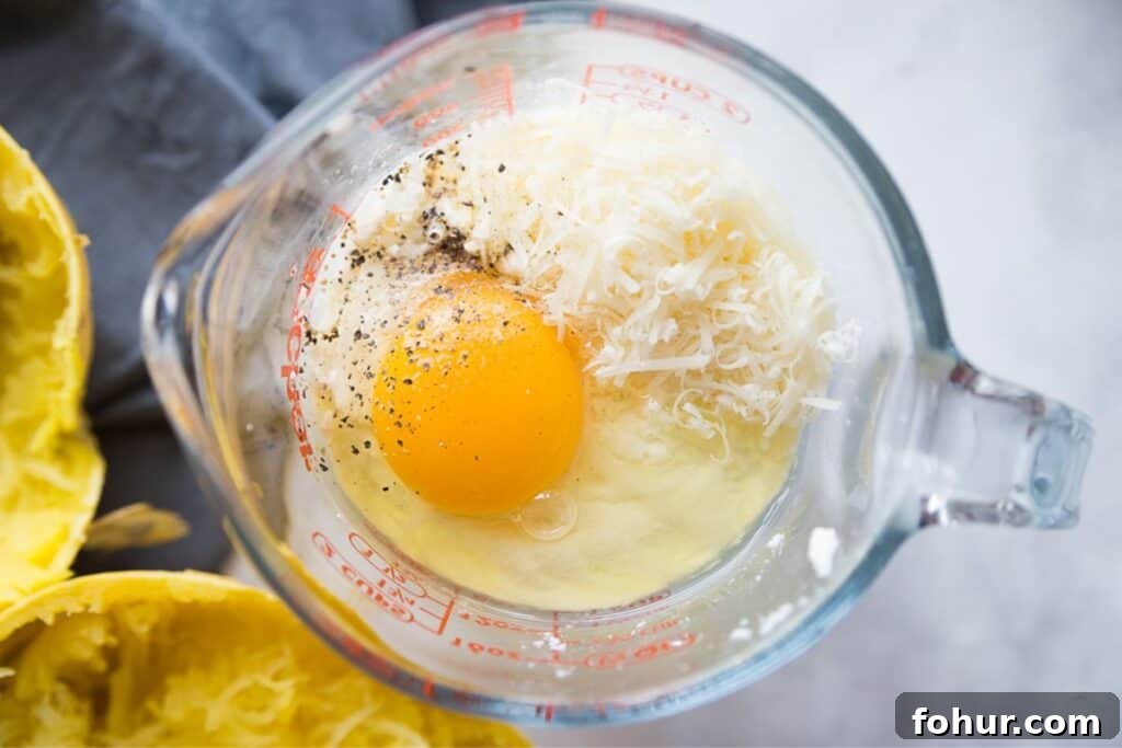 Low-Carb Spaghetti Squash Lasagna Recipe 5 Egg, ricotta, parmesan cheese, and pepper in a glass measuring cup.