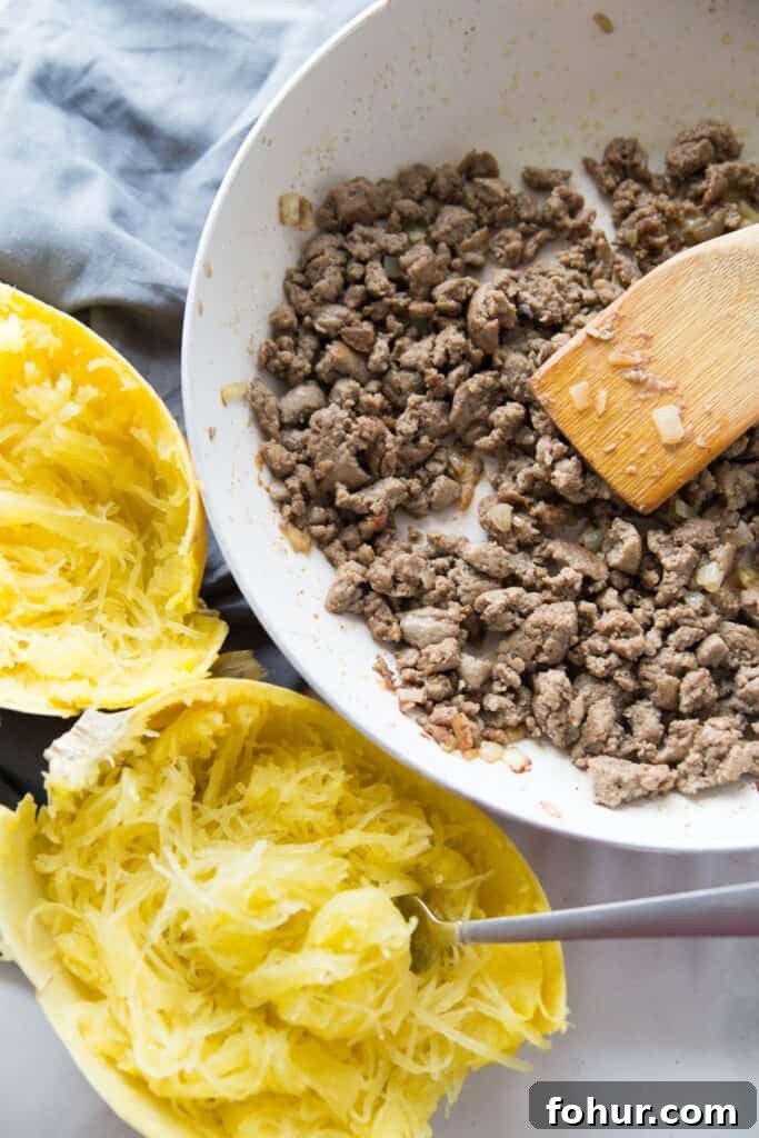 Low-Carb Spaghetti Squash Lasagna Recipe 6 A cooked spaghetti squash cut in half, and a bowl of cooked Italian chicken sausage.