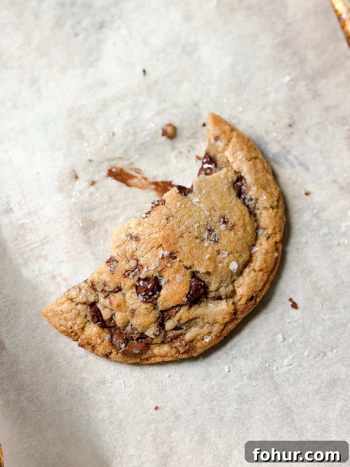 a broken piece of a single serve chocolate chip cookie with chocolate smeared.