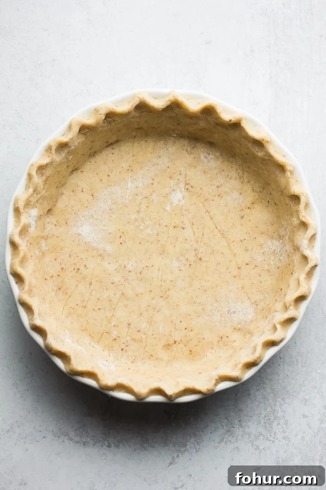 Flaky Vegan Gluten-Free Oil-Free Pie Crust Recipe 4 an uncooked healthy pie crust with grey background, nicely in pie pan