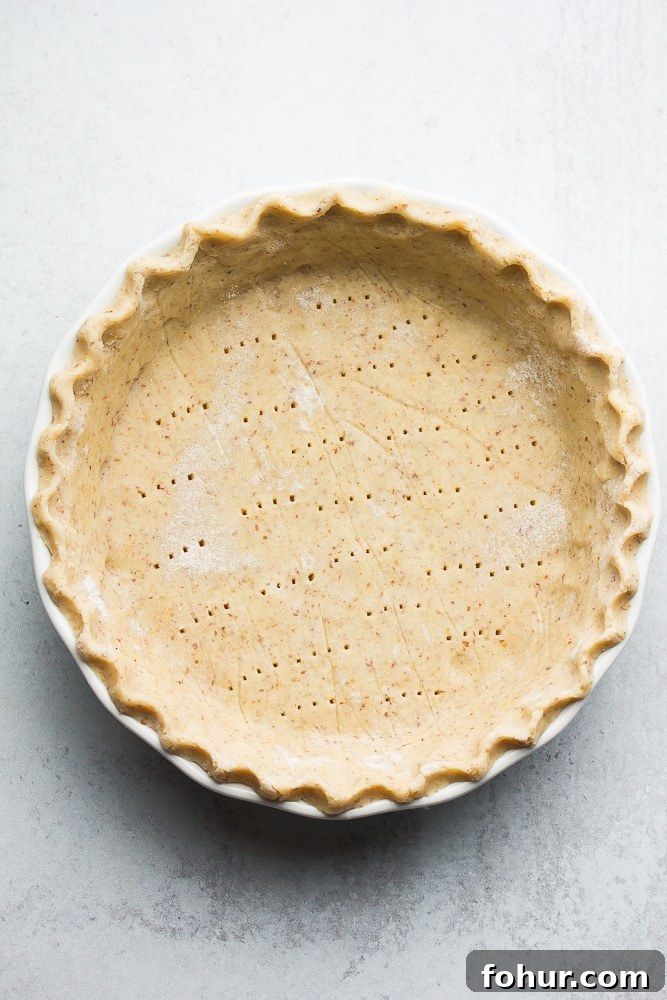 Flaky Vegan Gluten-Free Oil-Free Pie Crust Recipe 5 uncooked pie crust with fork holes in it, grey background