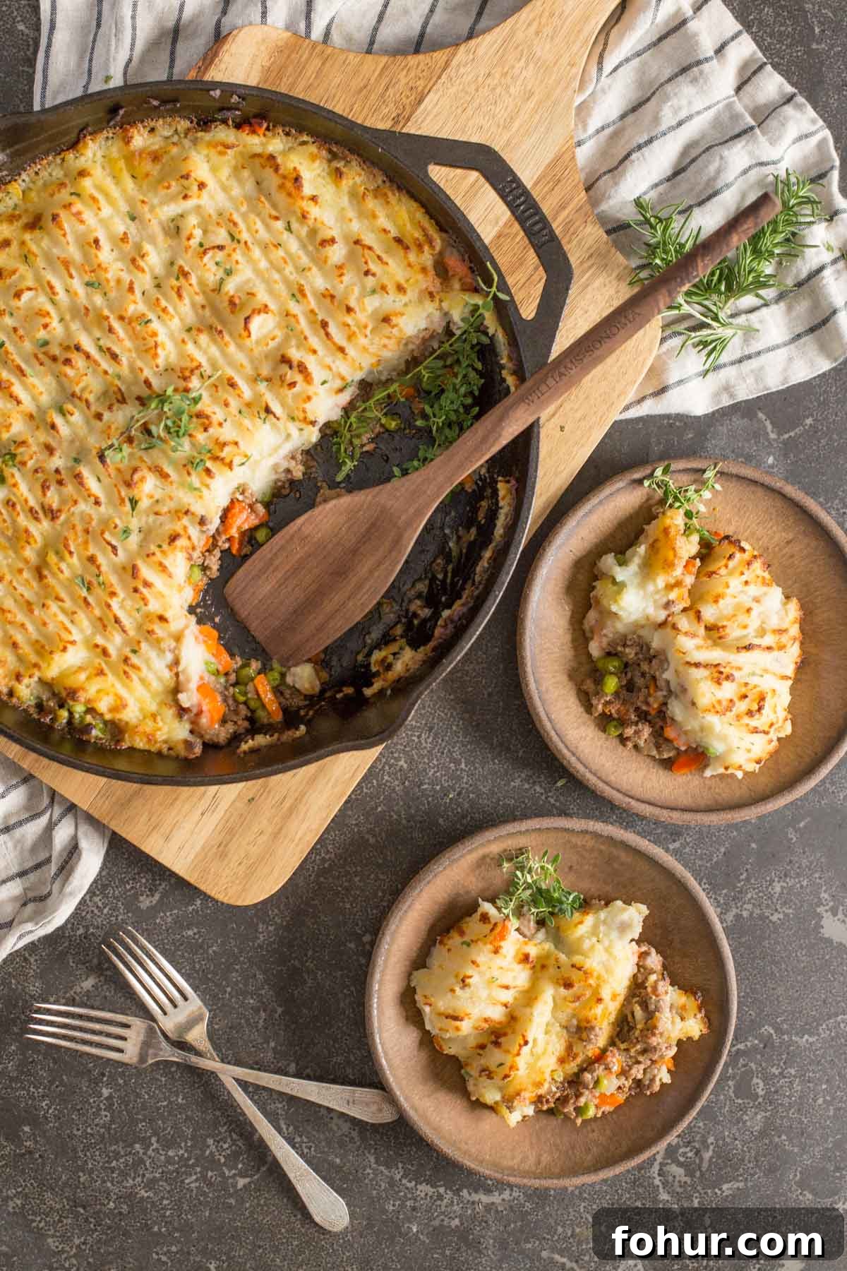 How to Clean a Cast Iron Skillet Without Stripping Seasoning 5 Two servings of Easy Homemade Shepherd's Pie dished on to two plates, with two forks next to them as well as the cast iron skillet of Easy Homemade Shepherd's Pie with a wooden spoon in it.