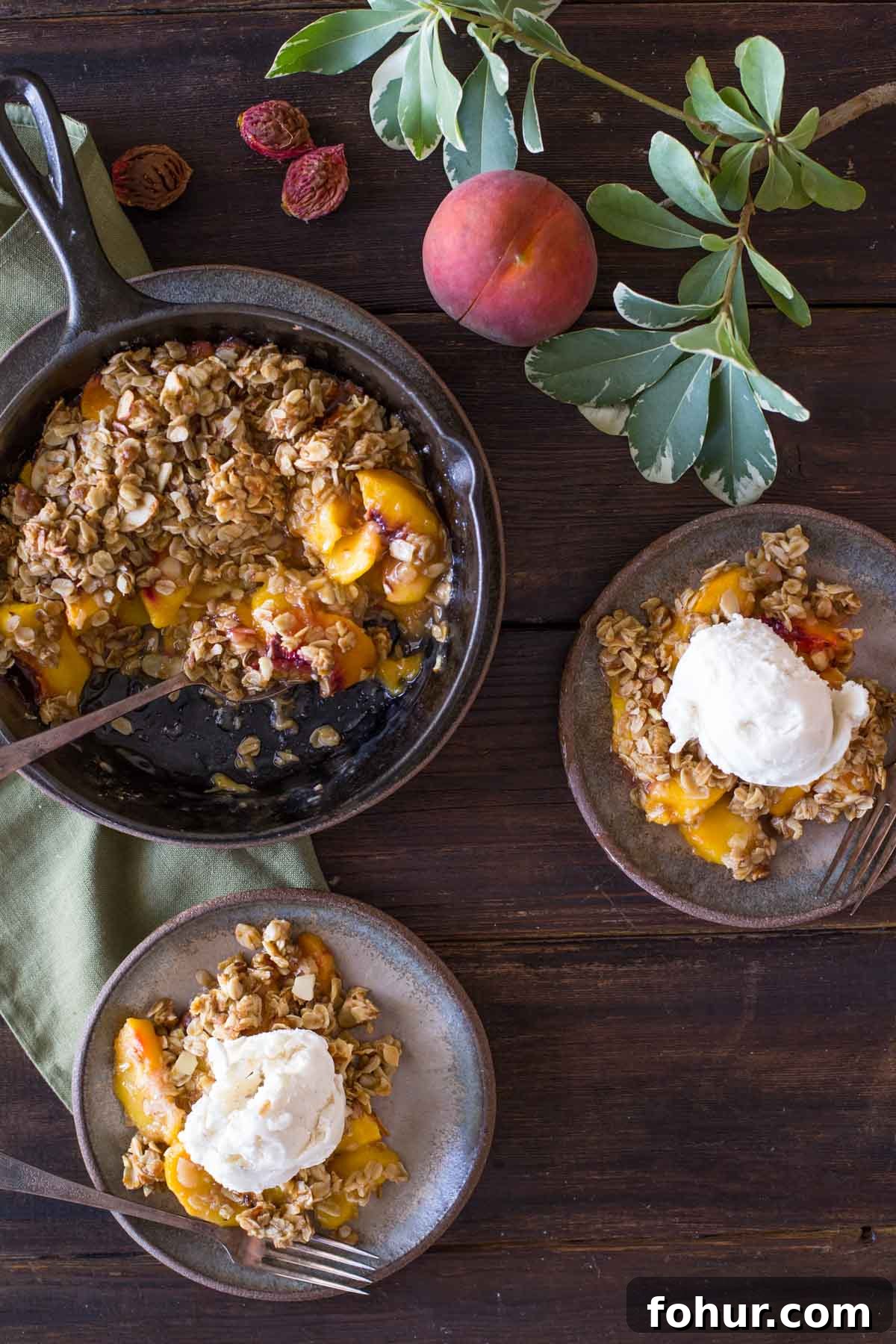 How to Clean a Cast Iron Skillet Without Stripping Seasoning 8 Two plates of Easy Skillet Peach Crisp topped with vanilla ice cream, sitting next to the skillet of Peach Crisp, as well as a whole peach and a few peach pits.