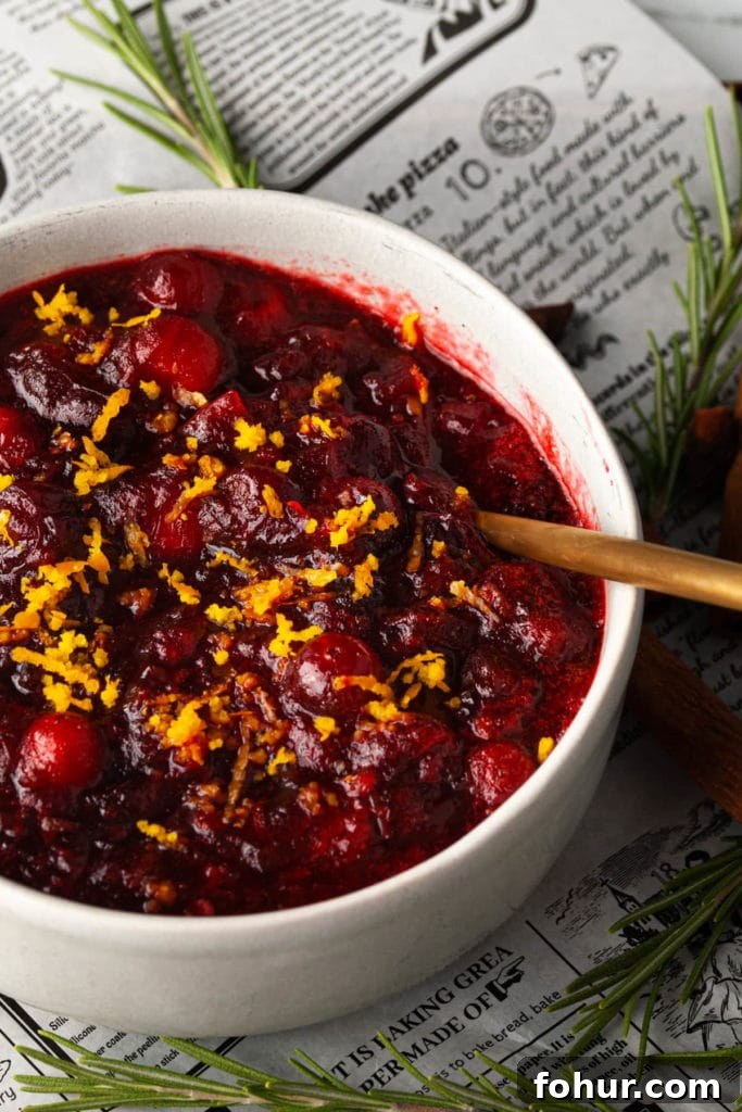 A bowl of cranberry sauce with orange zest sitting on newspaper.