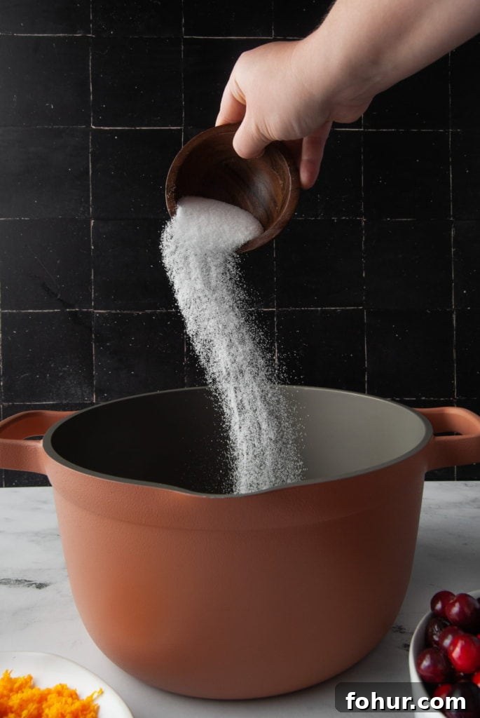 Adding sugar to a large pot to make cranberry sauce.