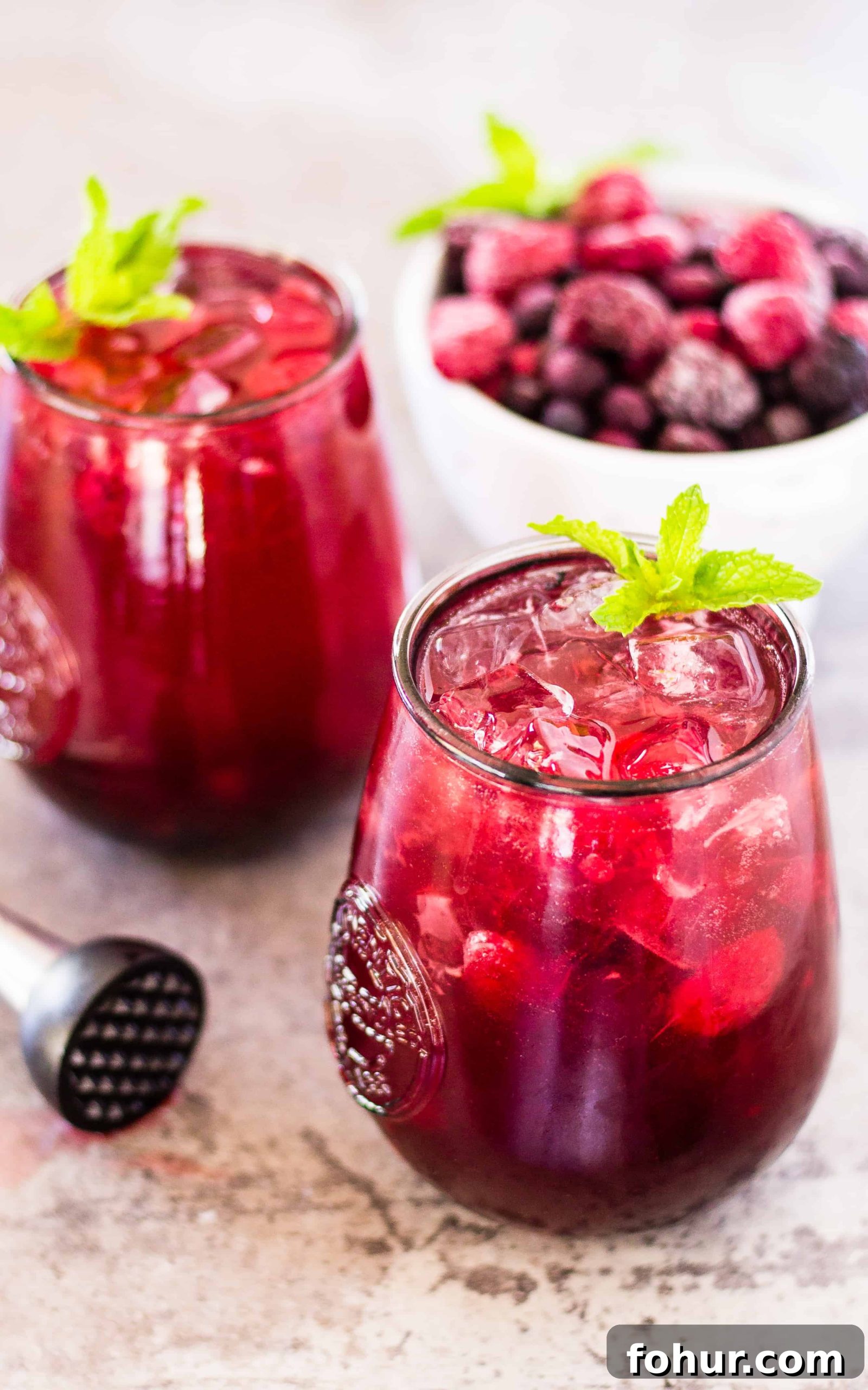 Low-Calorie Sangria Spritzer Recipe with Fresh Fruit 4 Side view of 2 skinny sangria spritzers and a bowl of berries on a table