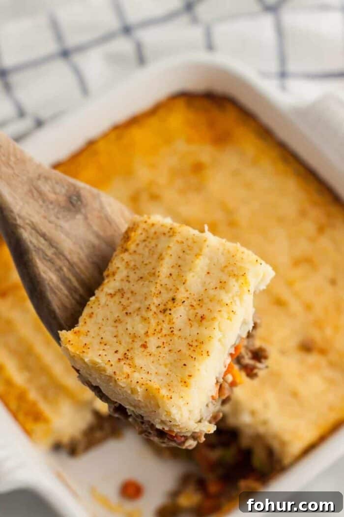 Crispy Keto Roasted Cauliflower with Parmesan 7 spoon holding up slice of keto shepherd's pie above a casserole dish