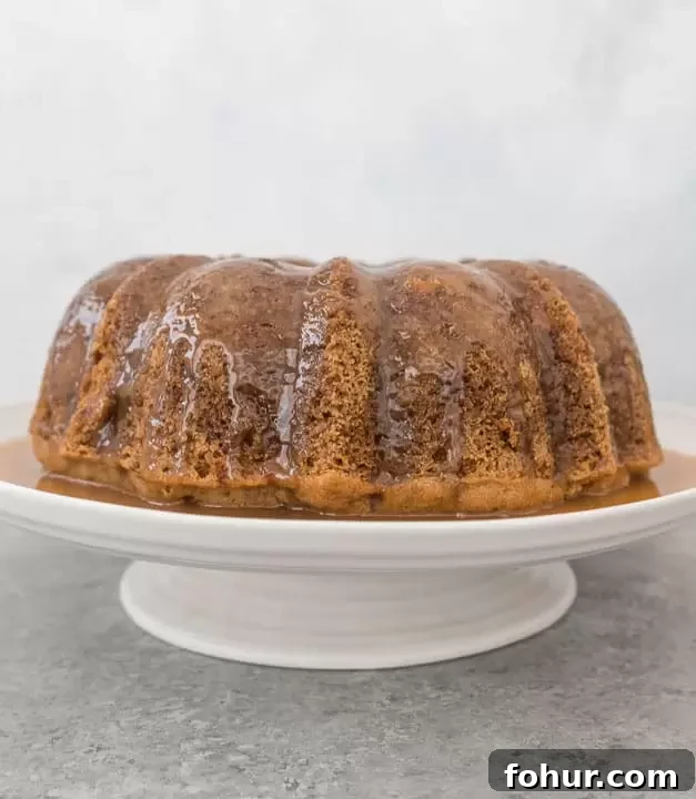 Moist Apple Bundt Cake with Warm Caramel Glaze 2 fresh apple bundt cake topped with caramel glaze sitting on a cake stand