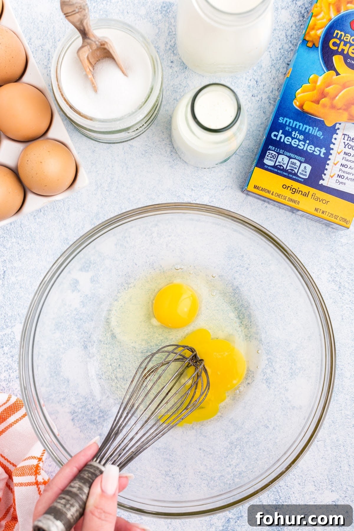 Copycat Mac and Cheese Ice Cream Recipe 4 Whisking eggs in a bowl, with other ingredients surrounding.