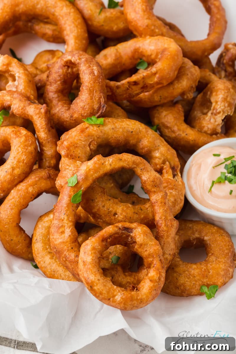 Crispy Gluten-Free Onion Rings Recipe 6 closeup view of a plate of onion rings on top of parchment paper.