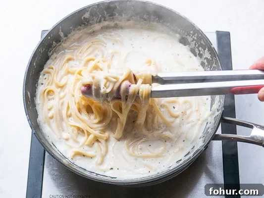 Creamy Fettuccine Alfredo: 30-Minute Vegetarian Recipe 7 Pasta being stirred into the Alfredo sauce