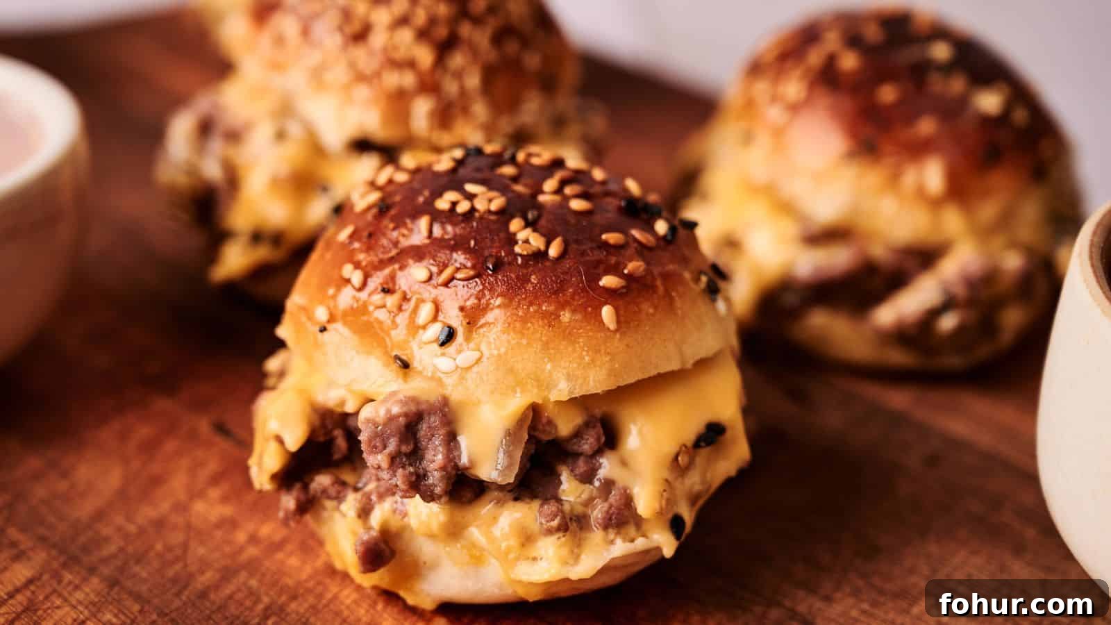31 New Year's Eve Snacks for Late-Night Parties 2 Three sesame seed buns filled with melted cheese and ground beef are arranged on a wooden board.