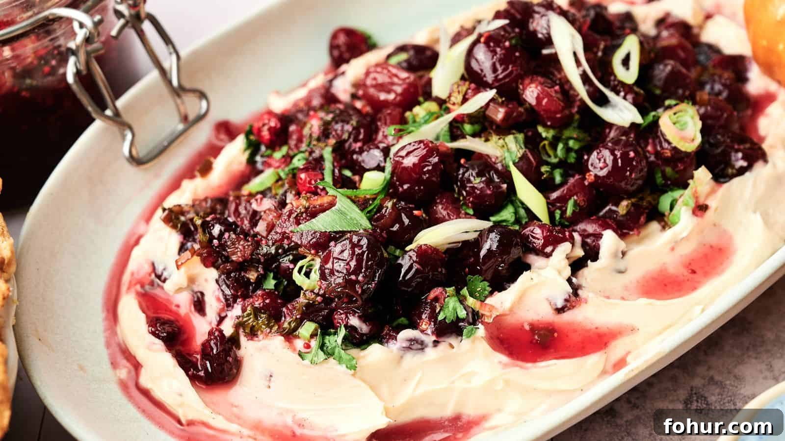 31 New Year's Eve Snacks for Late-Night Parties 30 A platter of whipped cheese topped with roasted cranberries, chopped herbs, and sliced green onions.