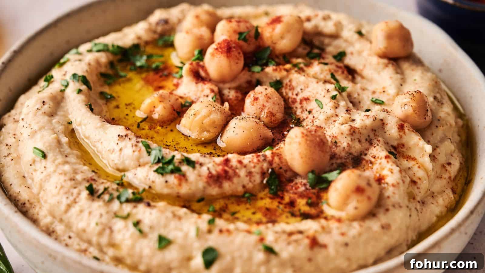 31 New Year's Eve Snacks for Late-Night Parties 7 A bowl of hummus garnished with whole chickpeas, chopped parsley, paprika, and a drizzle of olive oil.