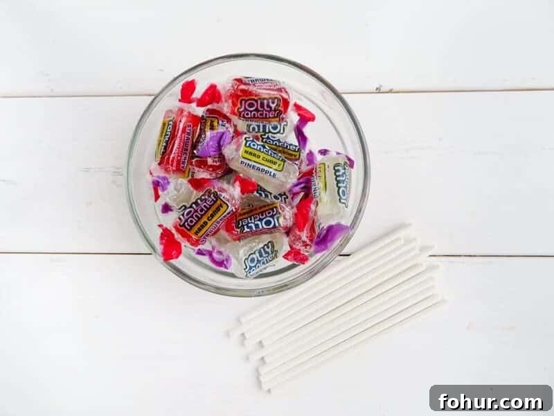 Red and white Jolly Ranchers in bowl with candy sticks besides them.