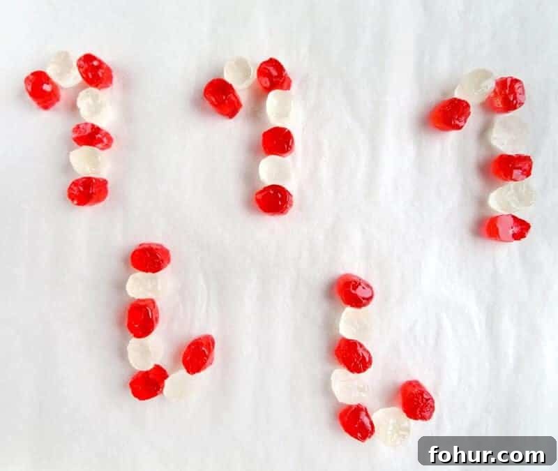 Cut jolly ranchers places on lined baking sheet in alternating red and white colors in shape of candy canes.