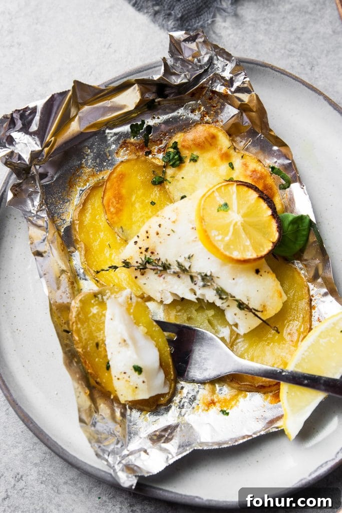 Lemon Herb Fish Baked in Foil with Potatoes 5 fish and potatoes baked in foil. A fish in foil packet on a plate with a fork