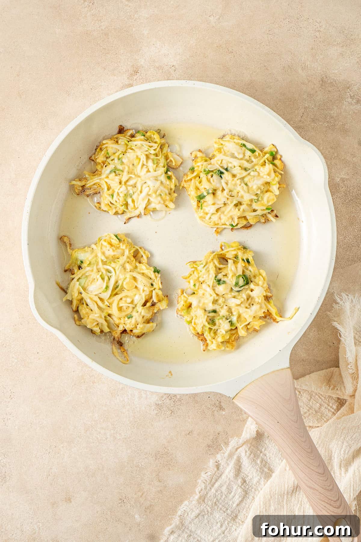 Crispy Cabbage Fritters Recipe with Tangy Yogurt Dip 6 The fritters in a frying pan.