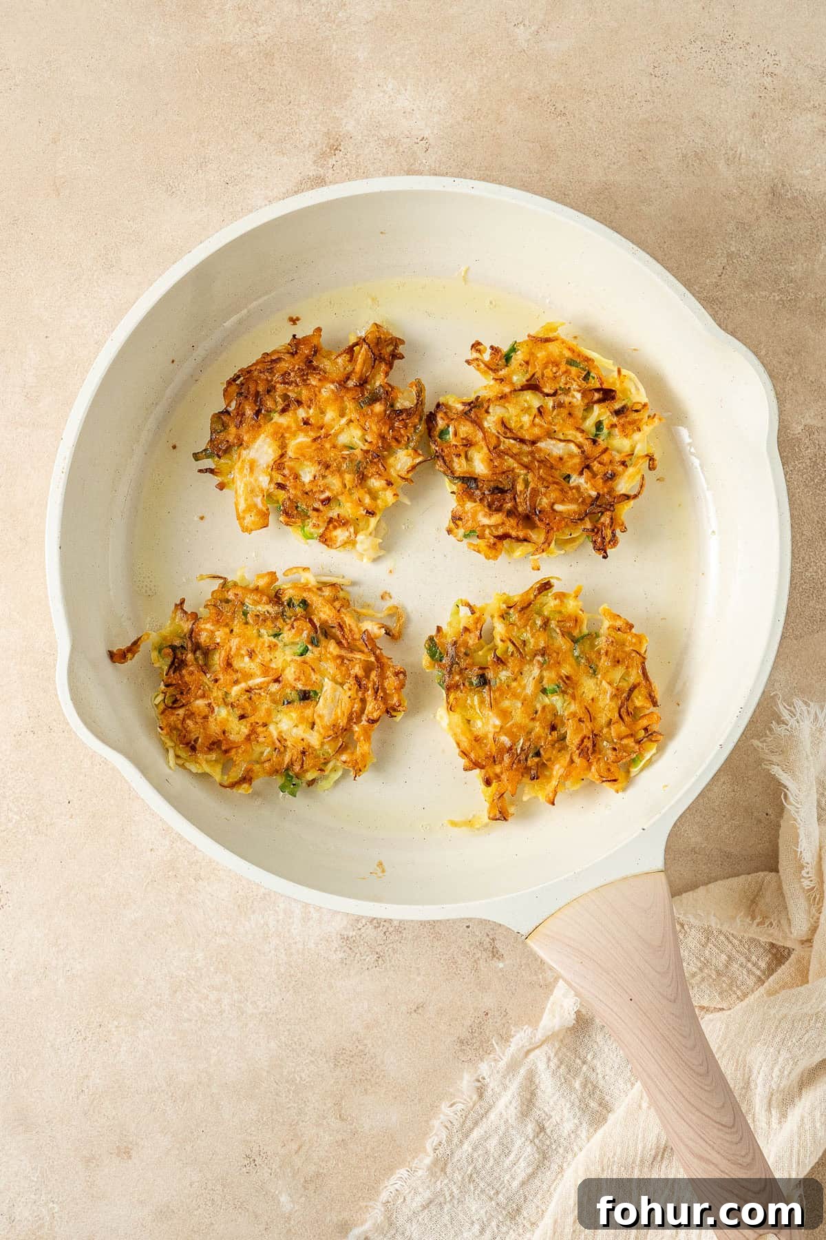 Crispy Cabbage Fritters Recipe with Tangy Yogurt Dip 7 The cooked fritters in a frying pan, golden and crispy.