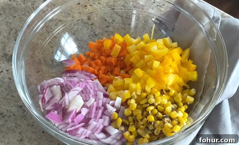 Ingredients laid out for salad: carrots, yellow pepper, red onion, corn